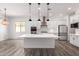 Spacious open kitchen featuring an island with seating, white cabinets, stainless steel appliances, and modern pendant lights at 26860 N 102Nd Ln, Peoria, AZ 85383
