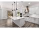 Open-concept kitchen featuring white cabinets, stainless steel hood, a large island, and pendant lighting at 26860 N 102Nd Ln, Peoria, AZ 85383