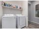 Bright laundry room featuring a modern washer and dryer, plus a shelf full of cleaning supplies at 26860 N 102Nd Ln, Peoria, AZ 85383
