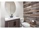 Stylish powder room features rustic wood accent wall, vanity with white countertop, and round mirror at 26860 N 102Nd Ln, Peoria, AZ 85383