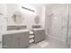 Bright bathroom featuring double vanities, round mirrors, tiled shower, and a patterned shower curtain at 29339 N 67Th Ave, Peoria, AZ 85383
