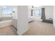 Bright main bedroom boasts neutral carpet, natural light, and ensuite bath with soaking tub and dual vanities at 29339 N 67Th Ave, Peoria, AZ 85383
