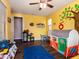 Bright bedroom with a large toy collection and a vibrant tree painting on the yellow accent wall at 3261 S Sunland Dr, Chandler, AZ 85248