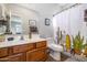 Bathroom with a wood vanity, framed mirror, and a shower/tub with a decorative cactus curtain at 3830 N Red Sky Cir, Mesa, AZ 85207