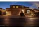 Inviting two-story home exterior with well-manicured landscaping and a three-car garage, illuminated at night at 3830 N Red Sky Cir, Mesa, AZ 85207