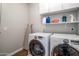 Well-organized laundry room with front-loading washer/dryer and upper cabinets at 3830 N Red Sky Cir, Mesa, AZ 85207