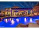 A gorgeous backyard at twilight featuring a luminous pool, lounge chairs and umbrella beneath a covered patio at 3830 N Red Sky Cir, Mesa, AZ 85207