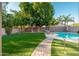 Beautiful backyard with lush green lawn, mature trees, a sparkling pool, and putting green at 4030 E Prickly Pear Trl, Phoenix, AZ 85050