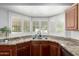 The kitchen sink features granite counter tops and white shuttered windows overlooking the exterior of the home at 4556 E Paradise Ln, Phoenix, AZ 85032