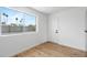 Bright bedroom featuring wood-look flooring, white walls, and a large window with neighborhood view at 4629 E Southern Ave, Phoenix, AZ 85042
