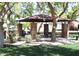 Outdoor gazebo with brick columns and a dark roof, surrounded by trees and green grass in a community park at 4747 E Narrowleaf Dr, Gilbert, AZ 85298