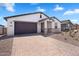 Attractive home showcasing desert landscaping, neutral tones, and a brick-paved driveway to the two car garage at 4811 W Hunter Trl, San Tan Valley, AZ 85144