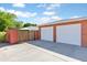 This is a two-car garage with a brick exterior and white doors with a concrete driveway and a wooden gate nearby at 502 W Windsor Ave, Phoenix, AZ 85003