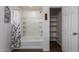 Well-lit bathroom featuring a tub with tile surround and a separate linen closet with shelves for storage at 5440 W Apollo Rd, Laveen, AZ 85339