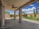 A covered patio with a ceiling fan and stone pillars overlooks the lush lawn, creating the perfect outdoor entertainment space at 5440 W Apollo Rd, Laveen, AZ 85339