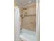 Shower with beige tile walls, a shelf, and a shower curtain at 5711 E Corrine Dr, Scottsdale, AZ 85254