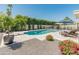 A backyard view of the large pool with diving board, surrounded by a patio, landscaping and an umbrella covered table at 5711 E Corrine Dr, Scottsdale, AZ 85254