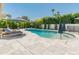 A kidney shaped pool is surrounded by lounge chairs and umbrellas and a fence for safety at 5711 E Corrine Dr, Scottsdale, AZ 85254
