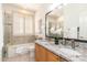 Bathroom featuring a double granite sink, tub, shutters, and tile walls at 6135 E Campo Bello Dr, Scottsdale, AZ 85254