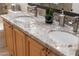 Bathroom featuring a double granite sink, wood cabinets, and brushed metal fixtures at 6135 E Campo Bello Dr, Scottsdale, AZ 85254
