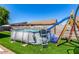 Backyard featuring above-ground pool with slide and ladder, surrounded by artificial grass at 630 E Racine Pl, Casa Grande, AZ 85122