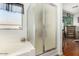Bright bathroom with a tub, enclosed shower, and neutral tile, complemented by natural light from the window at 630 E Racine Pl, Casa Grande, AZ 85122