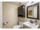 Powder room with a vintage mirror, mounted cabinet, and pedestal sink at 7469 E Timberlane Ct, Scottsdale, AZ 85258