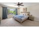 Bright bedroom featuring a large window, ceiling fan, and neutral color palette at 7469 E Timberlane Ct, Scottsdale, AZ 85258