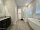 Modern bathroom featuring a standalone tub, walk-in shower, and sleek vanity at 8024 W State Ave, Glendale, AZ 85303
