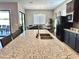 Granite island sink in modern kitchen with stainless steel appliances, dark cabinetry, and tile flooring at 8024 W State Ave, Glendale, AZ 85303