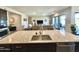 Modern kitchen island with stainless steel sink, tile floor, leading to connected living spaces at 8024 W State Ave, Glendale, AZ 85303