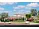 A luxurious home featuring a well-manicured lawn, mature trees, and a circular driveway, under a blue, partly cloudy sky at 10800 E Cactus Rd # 34, Scottsdale, AZ 85259
