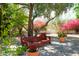 Secluded patio area with a brick surface, bench, and vibrant flowering plants at 10800 E Cactus Rd # 34, Scottsdale, AZ 85259
