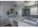 Bathroom with double sinks, granite countertops, and a large mirror, offering a functional and stylish space at 12503 W Vista Paseo Dr, Litchfield Park, AZ 85340