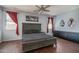 Spacious main bedroom featuring a king bed, dark wood floors, and bright windows with elegant red curtains at 12503 W Vista Paseo Dr, Litchfield Park, AZ 85340