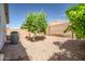 Backyard featuring gravel, a young tree, brick wall, and A/C unit, all under a clear blue sky at 13416 W Ventura St, Surprise, AZ 85379