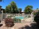 Community pool surrounded by fence, shrubs, trees, lounge chairs, and clubhouse at 15225 N 100Th St # 1220, Scottsdale, AZ 85260