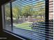 View from window with closed blinds overlooking a green lawn, trees, and a gated entrance to the community at 15225 N 100Th St # 1220, Scottsdale, AZ 85260