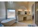 Bright bathroom featuring a soaking tub, dual sinks with granite countertops, and a glass shower at 15273 S 31St St, Phoenix, AZ 85048