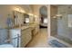 Bright bathroom featuring dual sinks, granite countertops, a glass shower, and access to the main bedroom at 15273 S 31St St, Phoenix, AZ 85048
