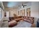 Inviting living room featuring a large brown leather sectional sofa and modern ceiling fan at 15273 S 31St St, Phoenix, AZ 85048