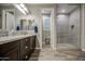 This bathroom features a double sink vanity, framed mirrors, and an adjacent glass-enclosed shower, combining style and practicality at 16042 W Shaw Butte Dr, Surprise, AZ 85379