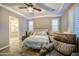 The main bedroom features a tray ceiling, ceiling fan, shuttered windows, and an ensuite bathroom with a glass door shower at 16042 W Shaw Butte Dr, Surprise, AZ 85379