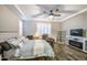 The main bedroom features a tray ceiling, a king bed, ceiling fan, TV, shuttered windows, and a comfortable reading chair at 16042 W Shaw Butte Dr, Surprise, AZ 85379