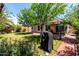 Large backyard featuring a covered patio area, lush grass, mature shade trees, and plant beds at 18622 N 28Th Way, Phoenix, AZ 85050