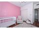 Bedroom featuring a white crib, light gray chair, pink accent wall, and wood-style flooring at 18807 N 42Nd Ave, Glendale, AZ 85308