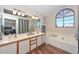 Bright main bathroom with double sinks, large window, soaking tub, and wood-style flooring at 18807 N 42Nd Ave, Glendale, AZ 85308