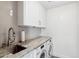 Clean laundry room featuring stainless steel appliances, marble countertop, and white cabinets at 2013 E Solano Dr, Phoenix, AZ 85016