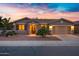 Charming single-story home featuring a two-car garage and desert landscaping against a colorful sunset sky at 20160 N Riverbank Rd, Maricopa, AZ 85138