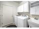 Functional laundry room with washer, dryer, utility sink, and storage cabinets at 20160 N Riverbank Rd, Maricopa, AZ 85138